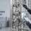 engineer comparing clamp, union, and flanged stainless steel sight glass connections on a vertical process equipment test skid